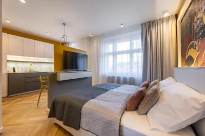 a bedroom with a large bed and a kitchen at Modern & Stylish Apartments Ječná in Prague