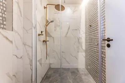 a bathroom with a shower with white marble walls at Modern & Stylish Apartments Ječná in Prague