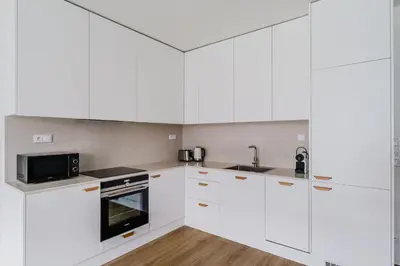 a white kitchen with white cabinets and a sink at Blueground Prague 7 furnished DOX museum PRG-25 in Prague