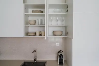 a kitchen counter with white cabinets with plates and glasses at Blueground Prague 7 furnished DOX museum PRG-25 in Prague