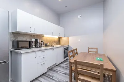 a kitchen with white cabinets and a wooden table at Selin Apartments in Prague