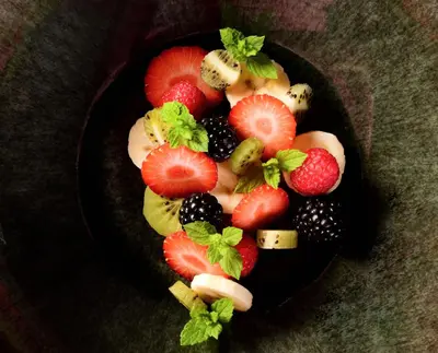 a black plate filled with fruit on a table at Apartmány Vinice Salabka in Prague