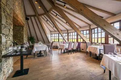 a dining room with tables and chairs and a stone wall at Apartmány Vinice Salabka in Prague