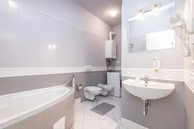 a white bathroom with a tub sink and a toilet at Veliant Apartments in Prague