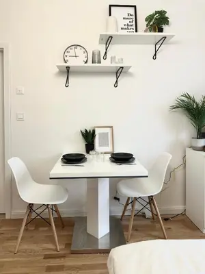 a white dining room table with two chairs and a clock at Rentero Prague Central Apartment in Prague