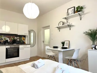 a bedroom with a bed and a kitchen with a desk at Rentero Prague Central Apartment in Prague