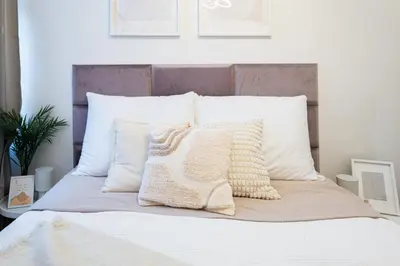a bed with white pillows on top of it at Rentero Apartment, 5 min National Muzeum Modern Black Rose in Prague