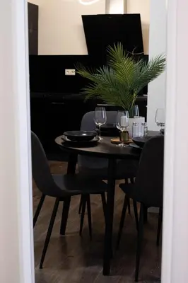 a dining room table with wine glasses and a potted plant at Rentero Apartment, 5 min National Muzeum Modern Black Rose in Prague
