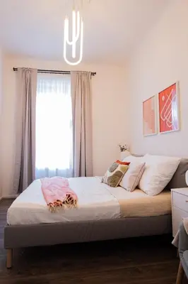 a bedroom with a large bed with a chandelier at Rentero Apartment, 5 min National Muzeum Modern Black Rose in Prague