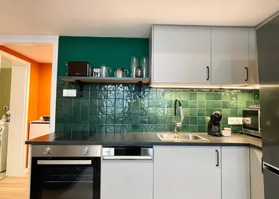 a kitchen with white cabinets and green tiles at La casa Prokop in Prague