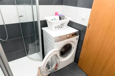 a washing machine in a bathroom with a shower at Staropramenna Garden Residence in Prague