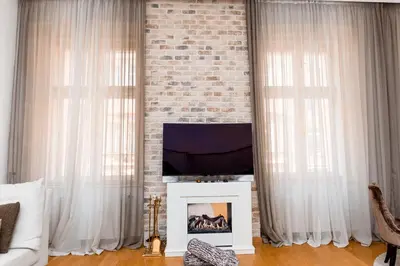 a living room with white curtains and a brick wall at Staropramenna Garden Residence in Prague
