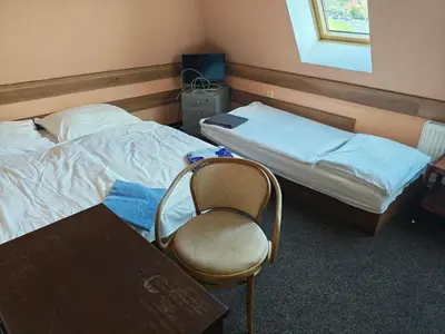 a room with two beds and a chair and a table at Motel Oseček in Oseček