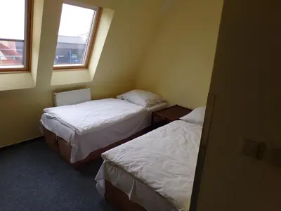 two beds in a small room with two windows at Motel Oseček in Oseček