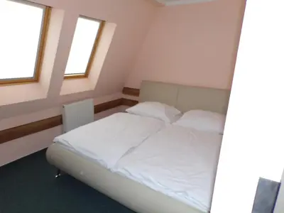 a bed in a small room with two windows at Motel Oseček in Oseček