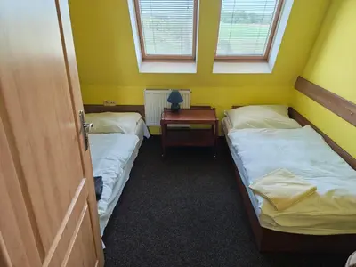two beds in a room with a table and two windows at Motel Oseček in Oseček