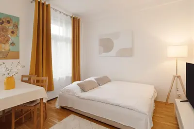 a white bedroom with a bed and a window at Louvre - Cozy City Center Apartment with Balcony in Prague