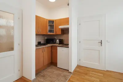 a kitchen with wooden cabinets and a white door at Louvre - Cozy City Center Apartment with Balcony in Prague