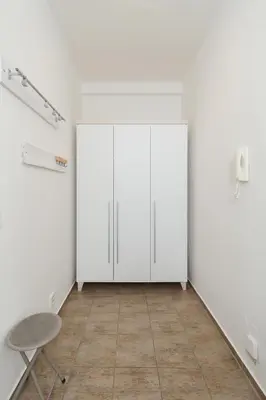 an empty room with white cabinets and a chair at Louvre - Cozy City Center Apartment with Balcony in Prague