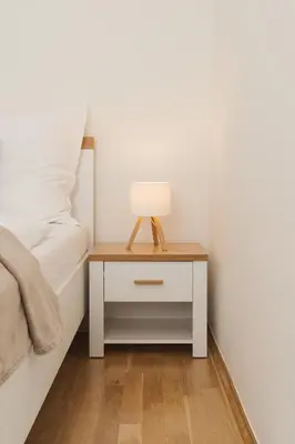 a nightstand with a lamp on it next to a bed at Louvre - Cozy City Center Apartment with Balcony in Prague