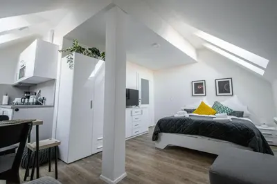 a white bedroom with a bed and a kitchen at Florenc Charming Studio in Prague