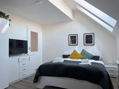 a white bedroom with a bed and a tv at Florenc Charming Studio in Prague