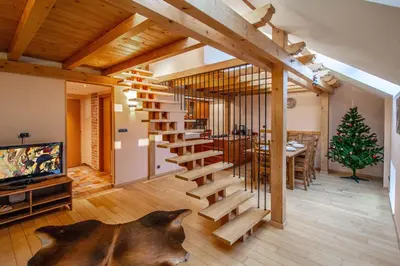 a wooden staircase in a living room with a christmas tree at Olives Ruterra Loft with Sauna in Prague