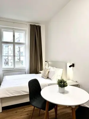 a white bedroom with a white bed and a table at Cozy One-Room Apartment in heart of Prague in Prague