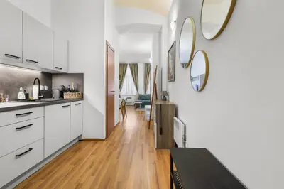 a kitchen with white cabinets and a wooden floor at Cozy stay near City Center - Žižkov in Prague