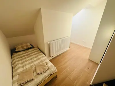 a small bedroom with a bed and a wooden floor at New sunny rooftop apartment with a terrace 10 minutes from city centre in Prague