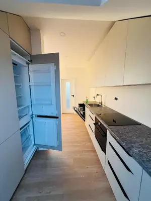 a kitchen with white cabinets and a blue open refrigerator at New sunny rooftop apartment with a terrace 10 minutes from city centre in Prague