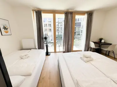 two beds in a room with a large window at Nest Home Prague center in Prague