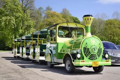 a green and white trolley car driving down a road at Hotel Konopiště Nová Myslivna in Benešov