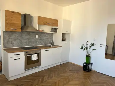 a kitchen with white cabinets and a wooden floor at Byt Podoli in Prague
