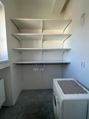 a laundry room with white shelves and a washing machine at Byt Podoli in Prague
