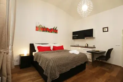 a bedroom with a bed and a desk and a television at Greg Apartments Kampa Prague in Prague
