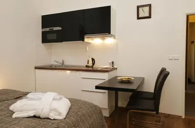 a room with a bed and a kitchen with a table at Greg Apartments Kampa Prague in Prague
