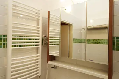a bathroom with a mirror and green tiles at Greg Apartments Kampa Prague in Prague