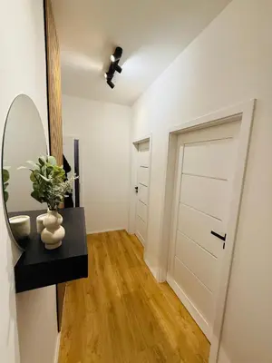a hallway with a white door and a vase on a table at Long Street Deluxe Suite Apartment Prague in Prague