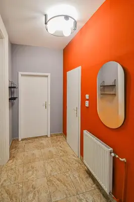 a hallway with an orange wall and a mirror at Celebration Flat by Ruterra in Prague