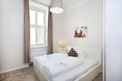 a white bedroom with a bed with white sheets at Celebration Flat by Ruterra in Prague