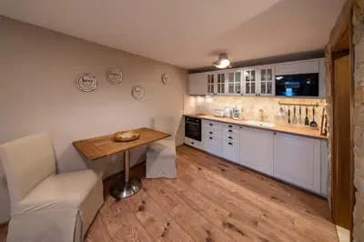 a kitchen with white cabinets and a wooden table at Studio Flat - Sleeps 3 - Parking - Wifi in Hostivice