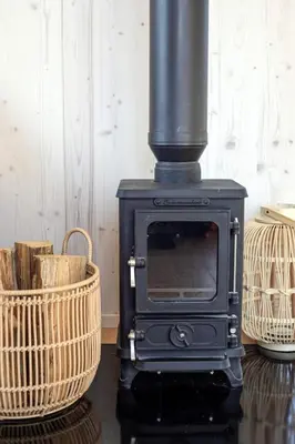 a black stove in a room with two baskets at Glamping Jezeroooo Lipence in Prague