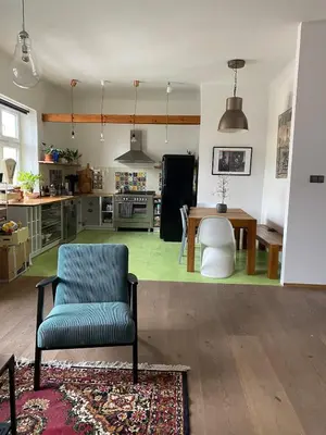 a living room with a blue chair and a kitchen at Colorful apartman in Holešovice in Prague