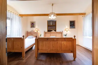 a bedroom with two wooden beds and a chandelier at Statek u Berků in Svatý Jan