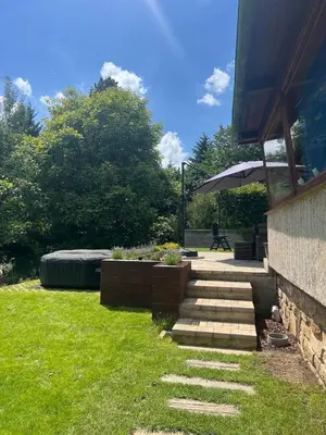 a garden with a patio with a bench and an umbrella at Chata Miracle in Slapy