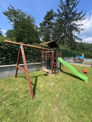 a playground with a green slide in the grass at Chata Miracle in Slapy