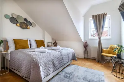 a white bedroom with a bed and a yellow chair at Duplex 165m2 with VIEWS only 30 Seconds to Charles Bridge in Prague