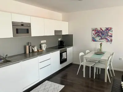 a kitchen with white cabinets and a table with chairs at Apartment Husova in Poděbrady