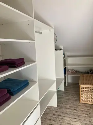 a white closet with white shelves and purple towels at Apartment Husova in Poděbrady